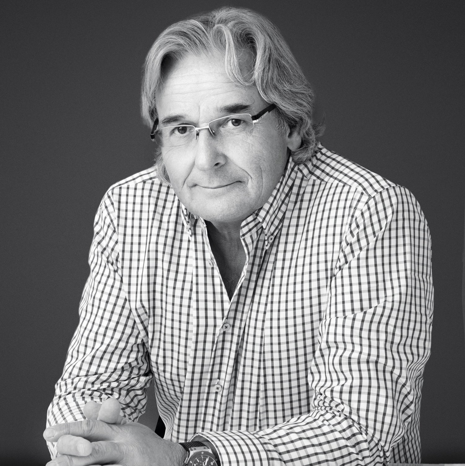 Professional headshot of a man in a checkered shirt, photographed in black and white.